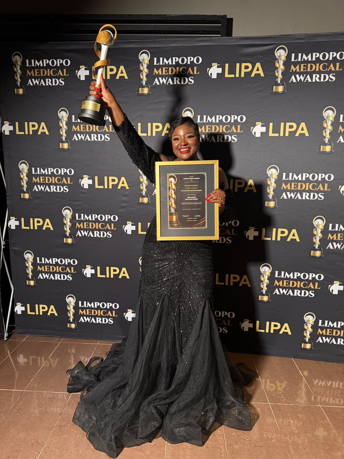 Dr Kholofelo Machaba-Selatole in front of the Limpopo Medical Awards backdrop with her trophy and certificate